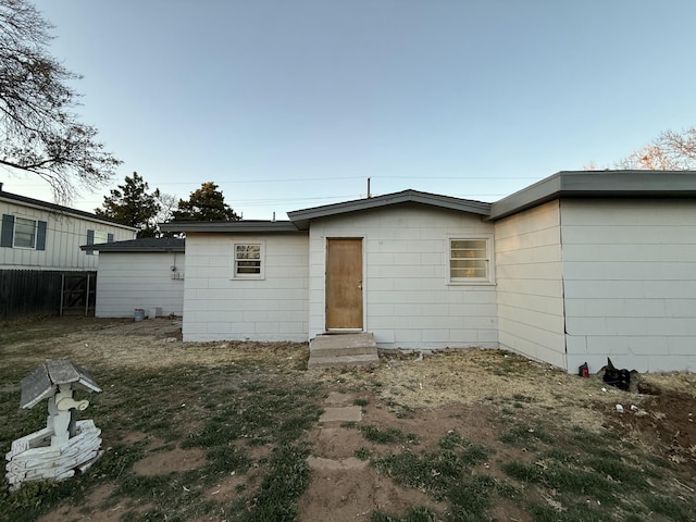 rear view of house featuring entry steps and fence