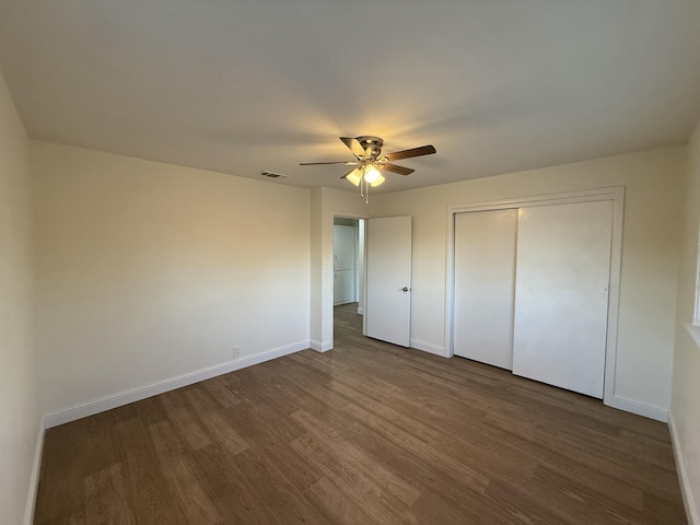 unfurnished bedroom featuring a closet, visible vents, dark wood-type flooring, ceiling fan, and baseboards