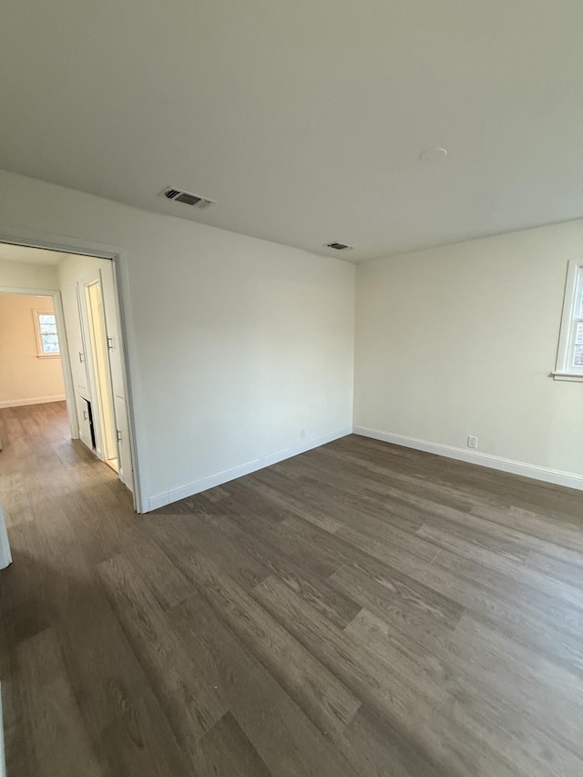 unfurnished room with dark wood-style floors, baseboards, and visible vents