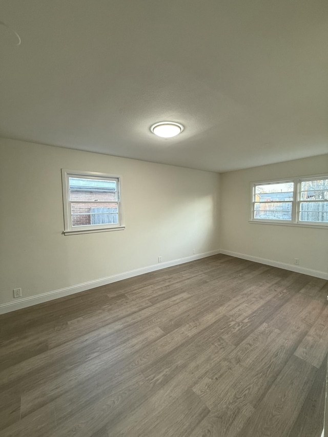 spare room with dark wood-type flooring and baseboards