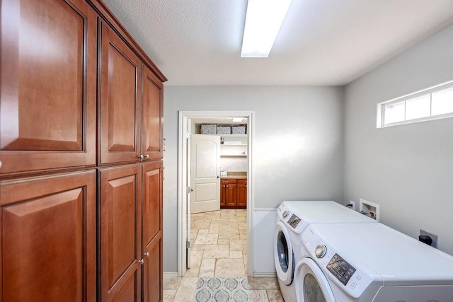 clothes washing area with cabinets, a textured ceiling, and independent washer and dryer