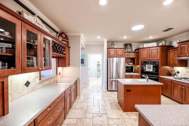 kitchen with crown molding, appliances with stainless steel finishes, sink, and a center island with sink