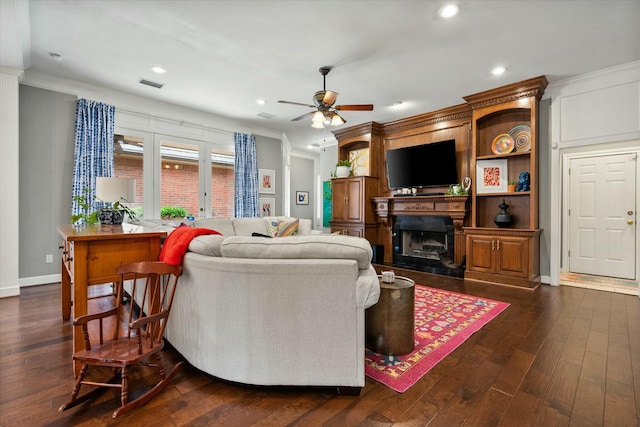 9214 York Pl, Lubbock, TX 79424 - living room featuring ceiling fan, crown molding, a fireplace with raised hearth, dark wood-style floors, and recessed lighting