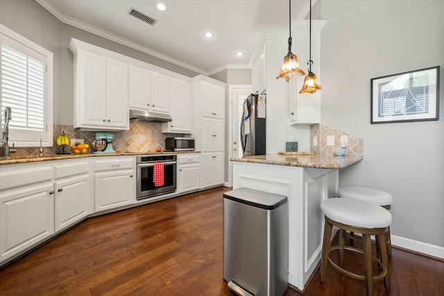 9214 York Pl, Lubbock, TX 79424 - kitchen featuring appliances with stainless steel finishes, under cabinet range hood, dark wood-type flooring, and visible vents