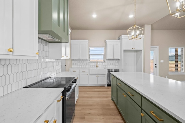 kitchen with pendant lighting, appliances with stainless steel finishes, range hood, and green cabinets