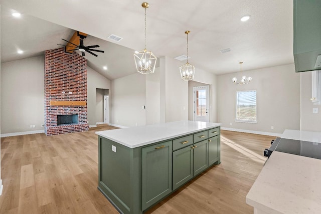 kitchen featuring pendant lighting, a center island, a fireplace, green cabinetry, and light wood-type flooring