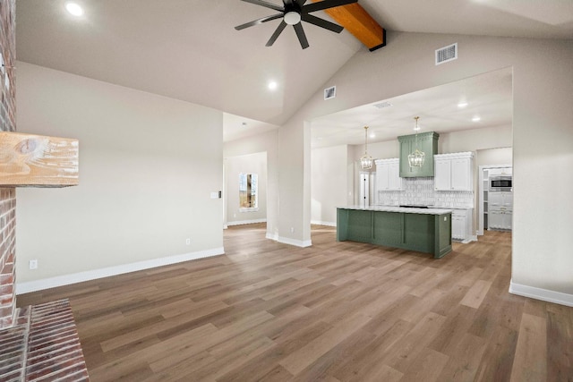 unfurnished living room with beam ceiling, light hardwood / wood-style flooring, high vaulted ceiling, and ceiling fan