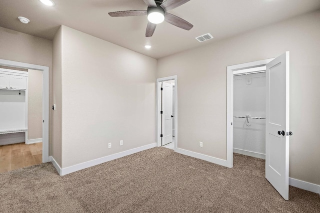 unfurnished bedroom with a spacious closet, a closet, ceiling fan, and carpet flooring