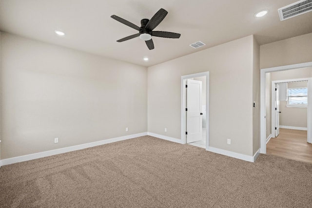 unfurnished bedroom featuring light carpet, ceiling fan, and ensuite bath