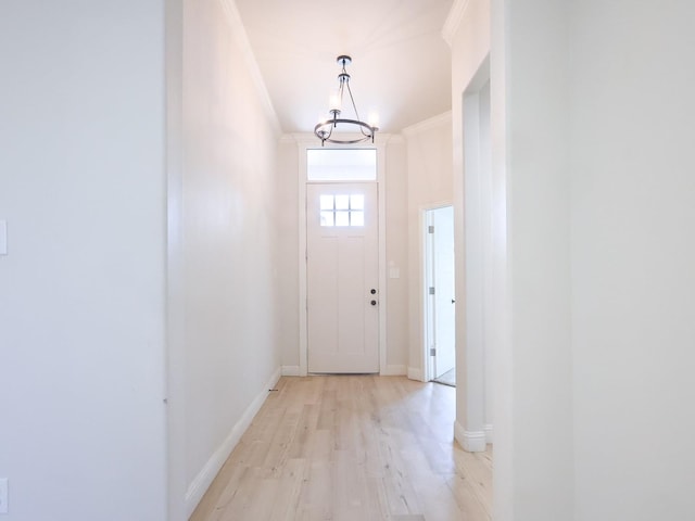 doorway with crown molding, an inviting chandelier, and light hardwood / wood-style flooring