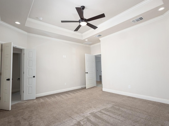 empty room with crown molding, light colored carpet, a raised ceiling, and ceiling fan