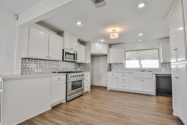 kitchen featuring appliances with stainless steel finishes, sink, white cabinets, and light hardwood / wood-style floors