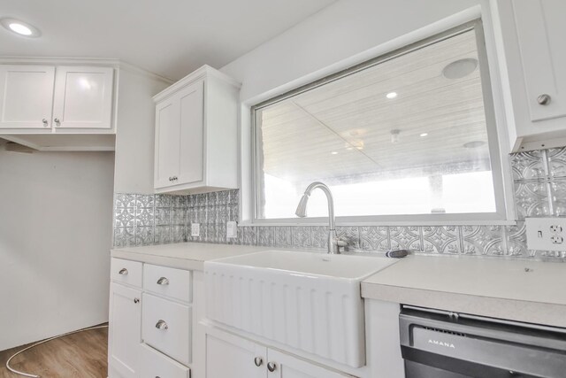 kitchen featuring sink, dishwasher, tasteful backsplash, wood-type flooring, and white cabinets