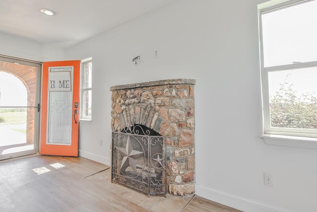 foyer featuring a stone fireplace, a wealth of natural light, and light hardwood / wood-style flooring