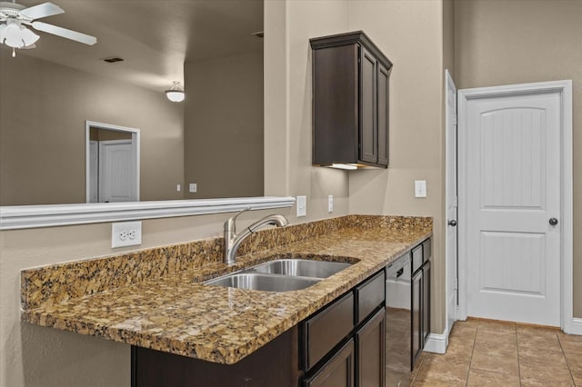 kitchen with stone counters, sink, light tile patterned floors, ceiling fan, and dark brown cabinets