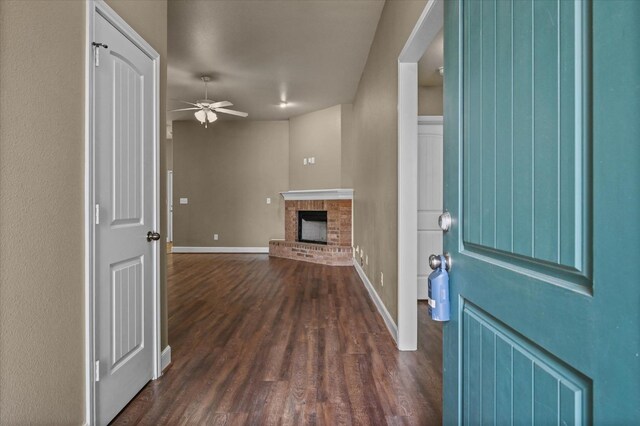 foyer entrance featuring dark hardwood / wood-style floors, ceiling fan, and a fireplace