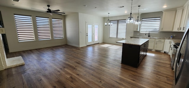 kitchen featuring open floor plan, a sink, white cabinetry, and a center island