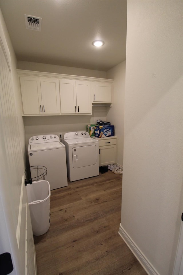 washroom with dark wood-style flooring, cabinet space, visible vents, independent washer and dryer, and baseboards