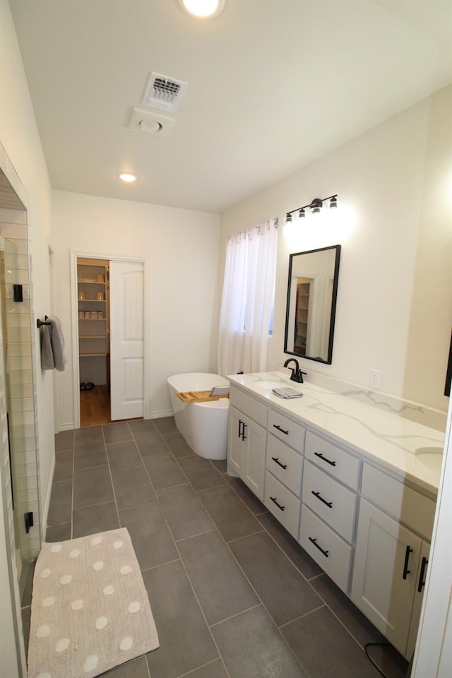 bathroom with double vanity, a stall shower, visible vents, a freestanding tub, and a sink