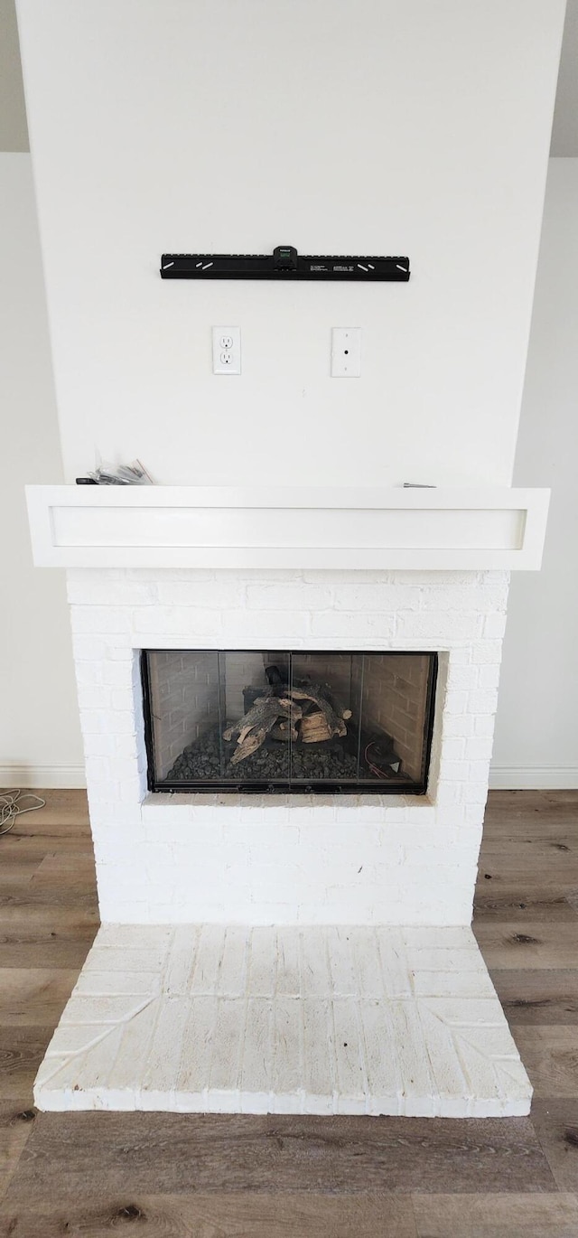 room details with a brick fireplace, baseboards, and wood finished floors