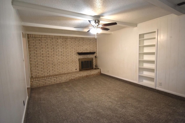 unfurnished living room featuring built in shelves, a brick fireplace, a textured ceiling, dark carpet, and beam ceiling