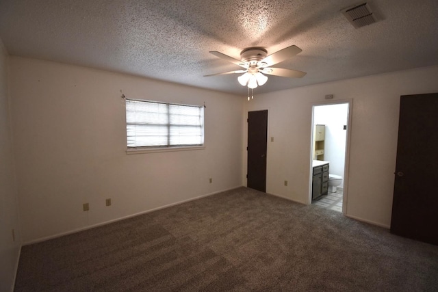 unfurnished bedroom with carpet, a textured ceiling, ceiling fan, and ensuite bath