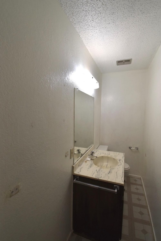 bathroom with vanity, toilet, and a textured ceiling