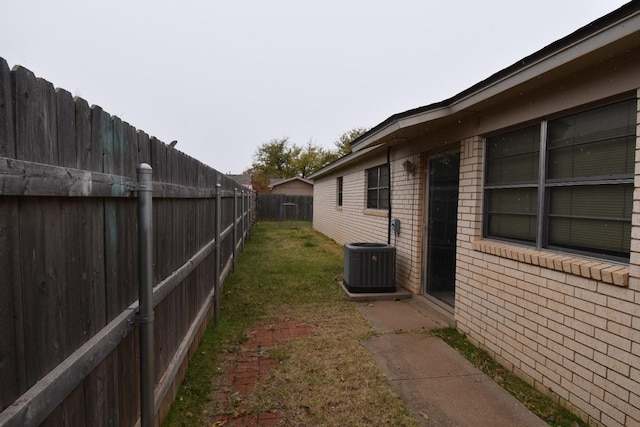 view of side of property featuring central AC unit and a yard