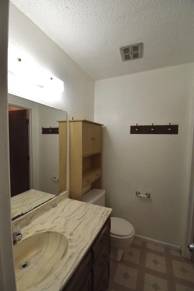 bathroom featuring vanity, a textured ceiling, and toilet