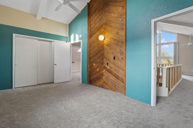 unfurnished bedroom featuring lofted ceiling with beams, carpet, ceiling fan, and a closet