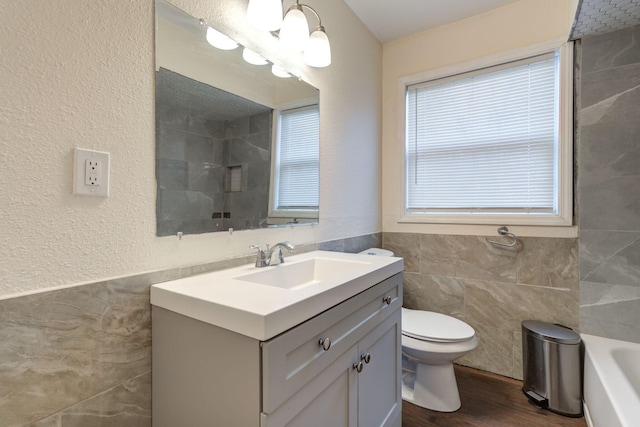 full bathroom with shower with separate bathtub, wood-type flooring, tile walls, vanity, and toilet