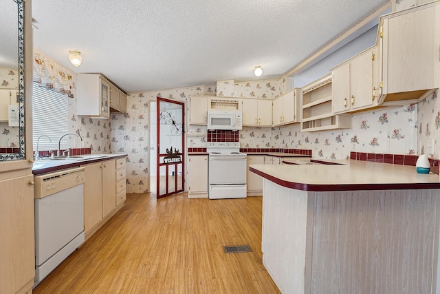 kitchen with lofted ceiling, sink, white appliances, light hardwood / wood-style floors, and a textured ceiling