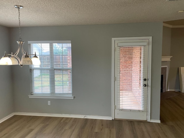 unfurnished dining area featuring hardwood / wood-style flooring, a healthy amount of sunlight, and an inviting chandelier