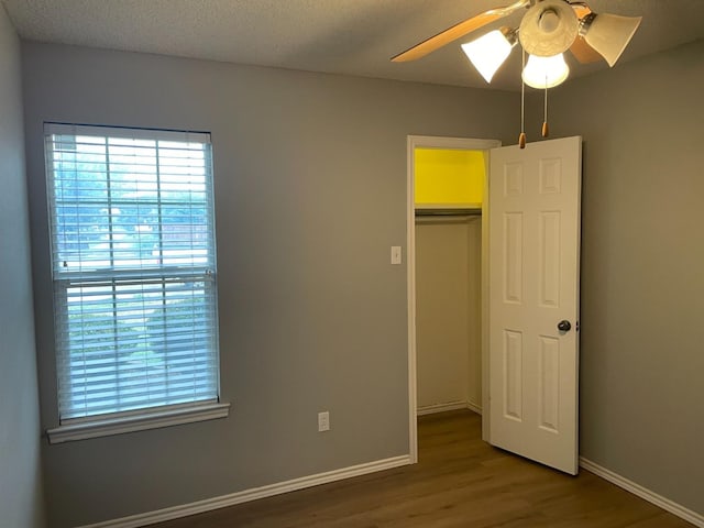 unfurnished bedroom featuring ceiling fan, wood-type flooring, a closet, and a textured ceiling