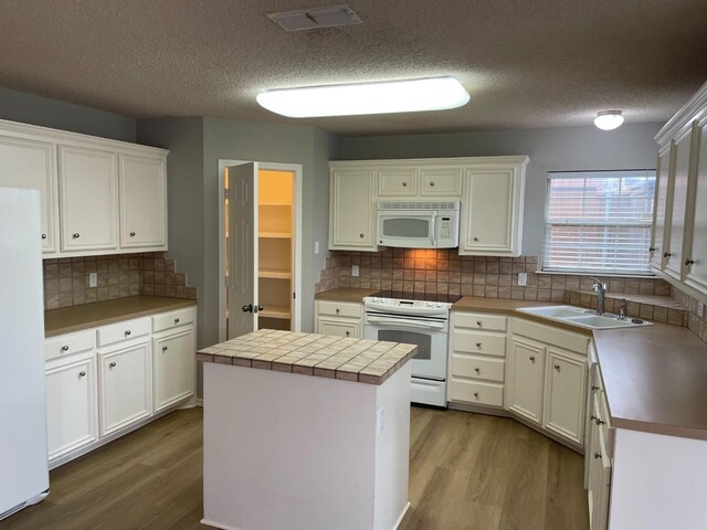 kitchen with a kitchen island, white cabinetry, wood-type flooring, sink, and white appliances