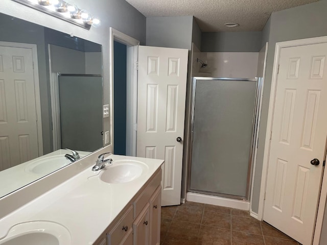 bathroom featuring vanity, an enclosed shower, tile patterned flooring, and a textured ceiling