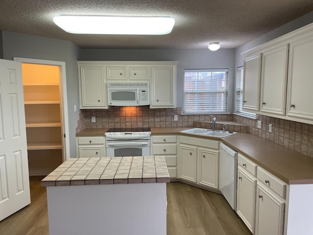 kitchen featuring white cabinetry, white appliances, sink, and a kitchen island