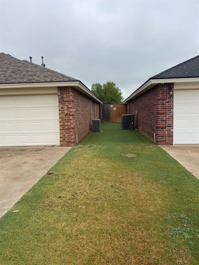 view of side of property with central AC and a lawn