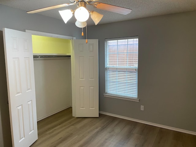 unfurnished bedroom featuring hardwood / wood-style flooring, a closet, ceiling fan, and a textured ceiling