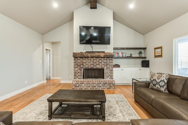 living room featuring lofted ceiling, a brick fireplace, and light hardwood / wood-style flooring