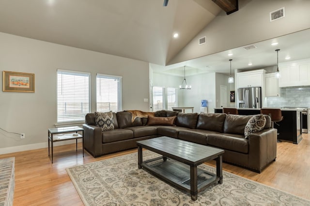 living room with beam ceiling, light hardwood / wood-style flooring, high vaulted ceiling, and a chandelier