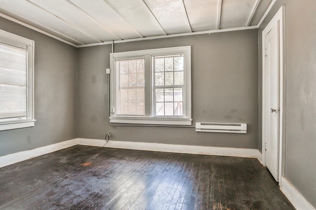 spare room with dark wood-type flooring and a baseboard radiator