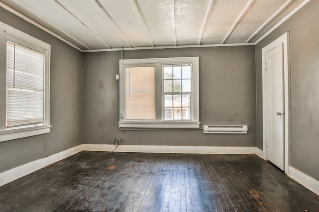 empty room featuring dark wood-type flooring and a baseboard radiator