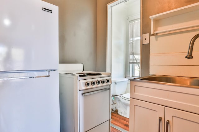 kitchen featuring white cabinetry, white appliances, sink, and light wood-type flooring