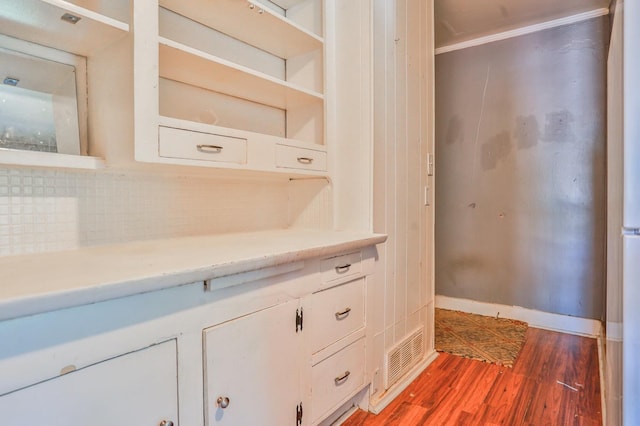 kitchen featuring crown molding, hardwood / wood-style flooring, and white cabinets