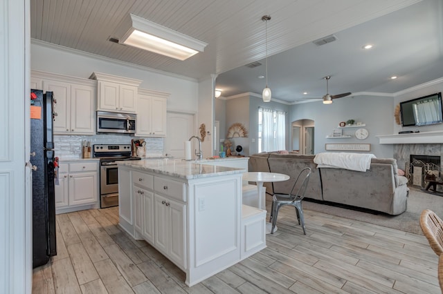 kitchen featuring stainless steel appliances, visible vents, open floor plan, and ornamental molding
