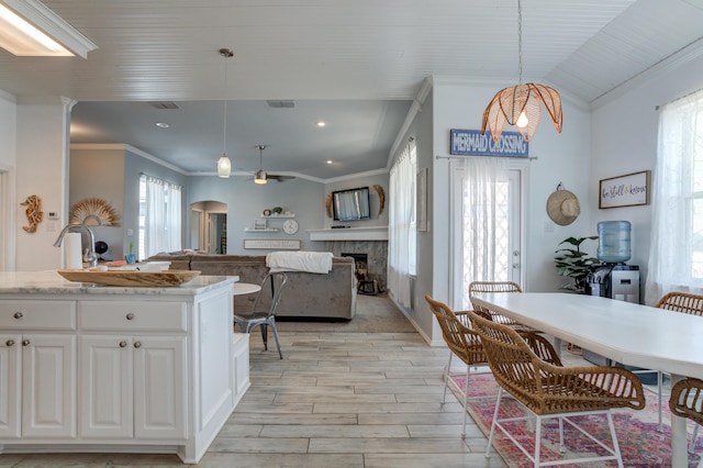 kitchen with a healthy amount of sunlight, visible vents, light wood-style floors, ceiling fan with notable chandelier, and a fireplace