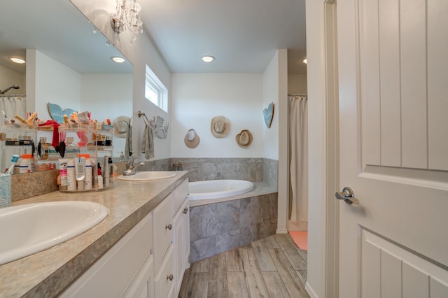 full bath featuring a bath, wood finished floors, a sink, and double vanity