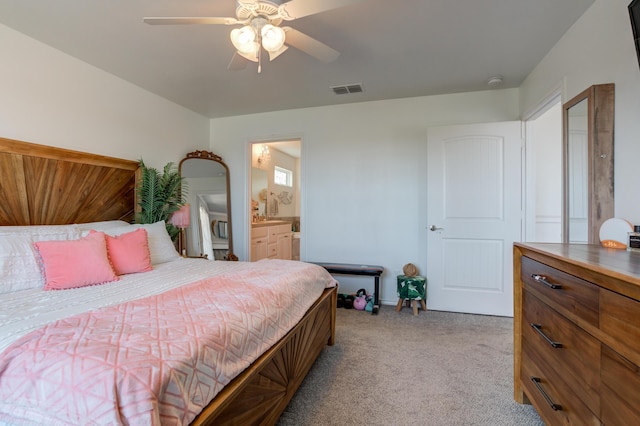 bedroom with ensuite bath, visible vents, a ceiling fan, and light colored carpet
