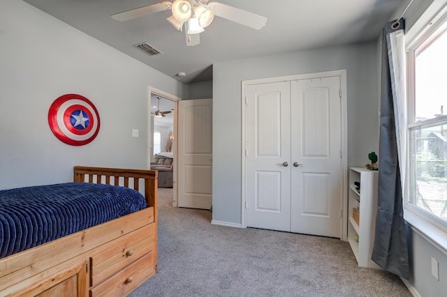 carpeted bedroom featuring a ceiling fan, visible vents, and a closet